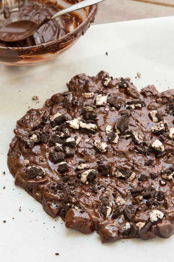 Dark chocolate bark recipe with oreo cookies spread on parchment paper.