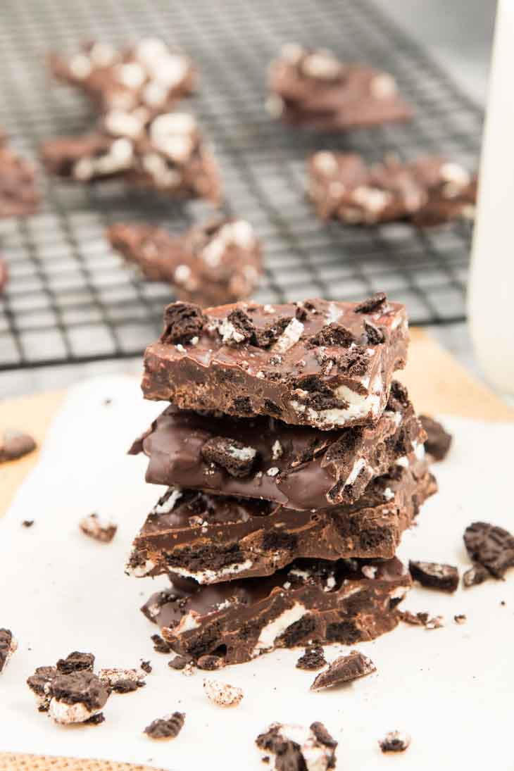 Side photograph of chocolate bark recipe stacked in a group of 4 with pieces of cookies around the side.