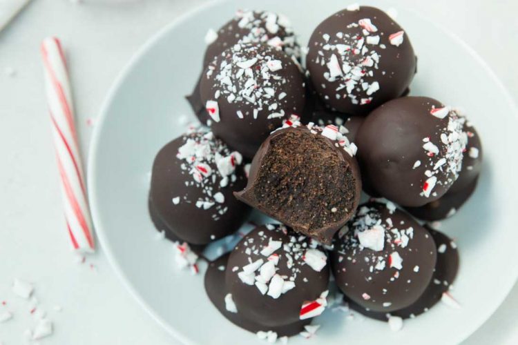 A plate of vegan brownie truffles with candy canes. The top truffle is half eaten.