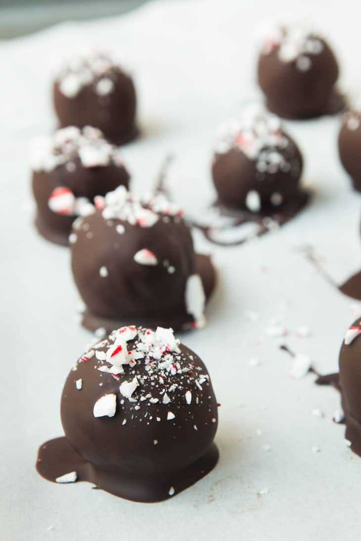 Peppermint Vegan Gluten-free Brownie truffles on a parchment lined baking sheet covered in chocolate.